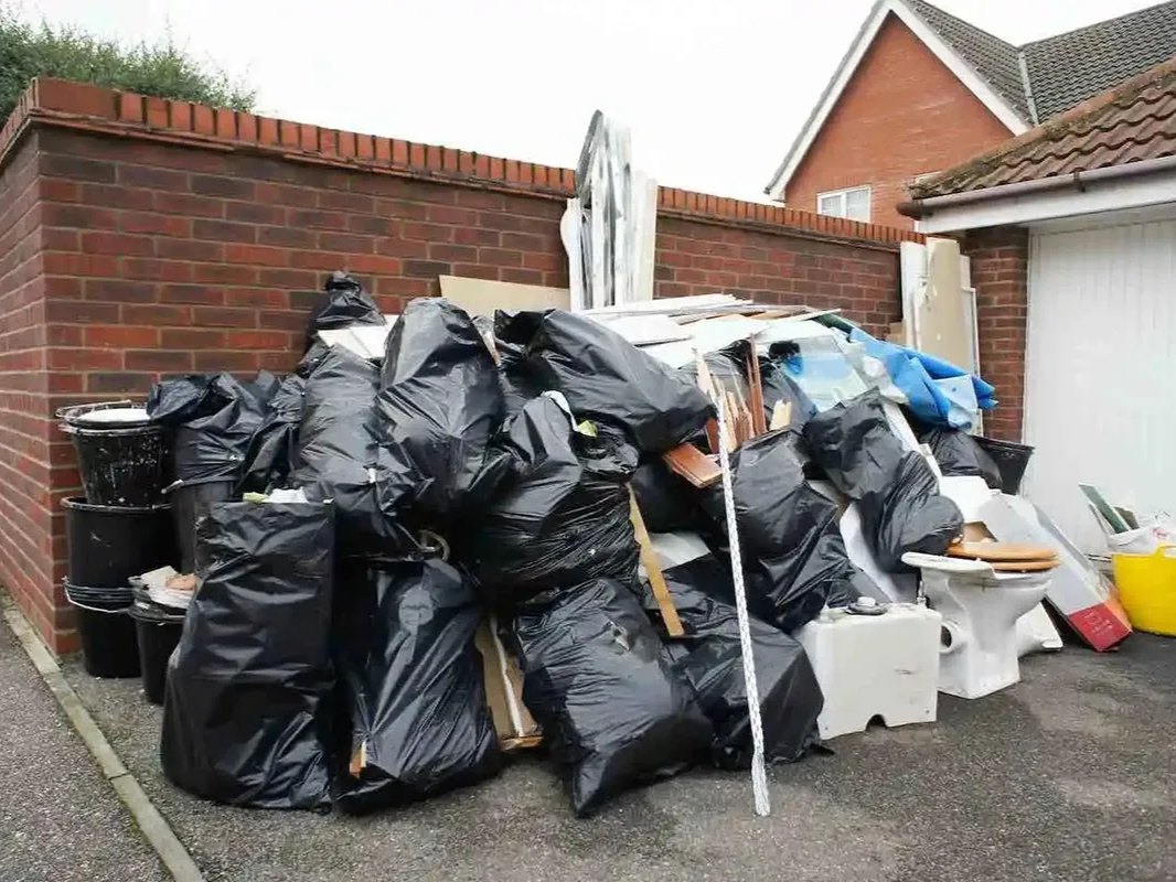A pile of trash bags and other debris is stacked