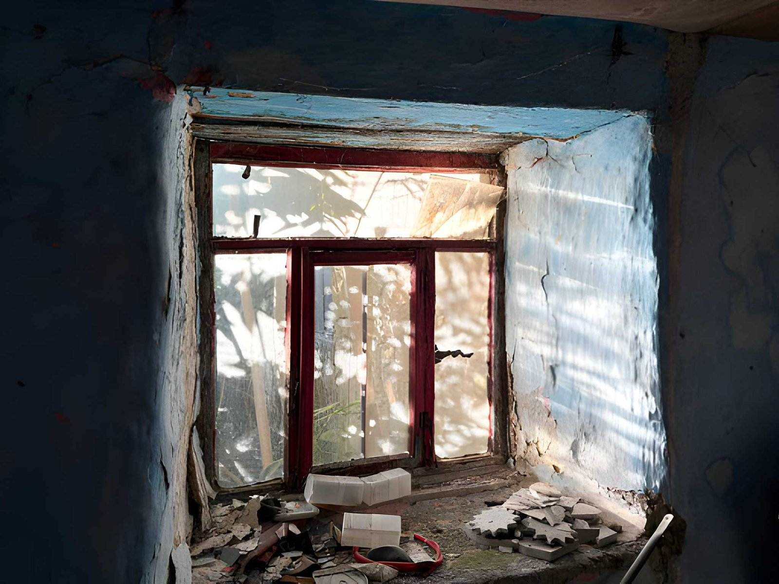 A room with a window and debris on the floor